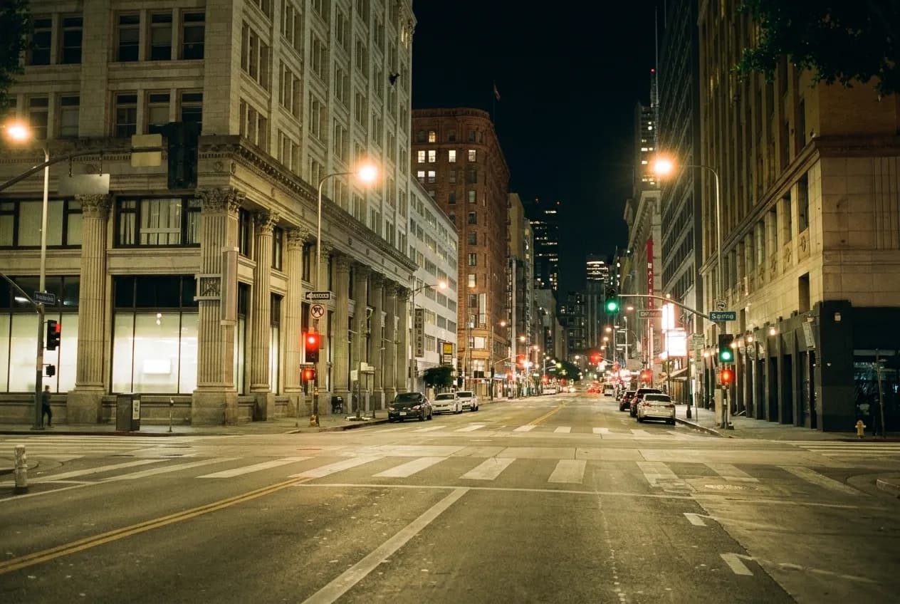 An empty city street at night with lit signage glow and parked cars in Los Angeles