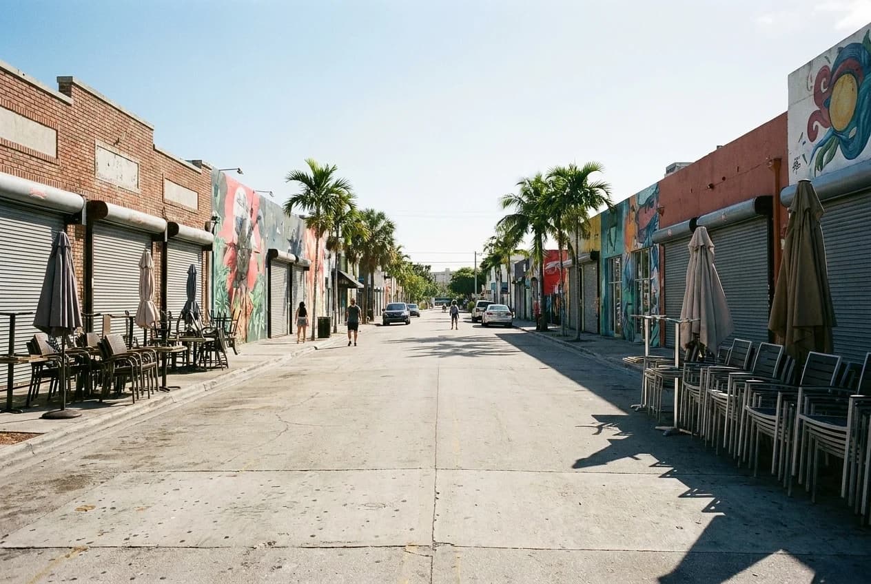 Closed restaurant storefronts with metal security gates along a Wynwood street on a weekday afternoon