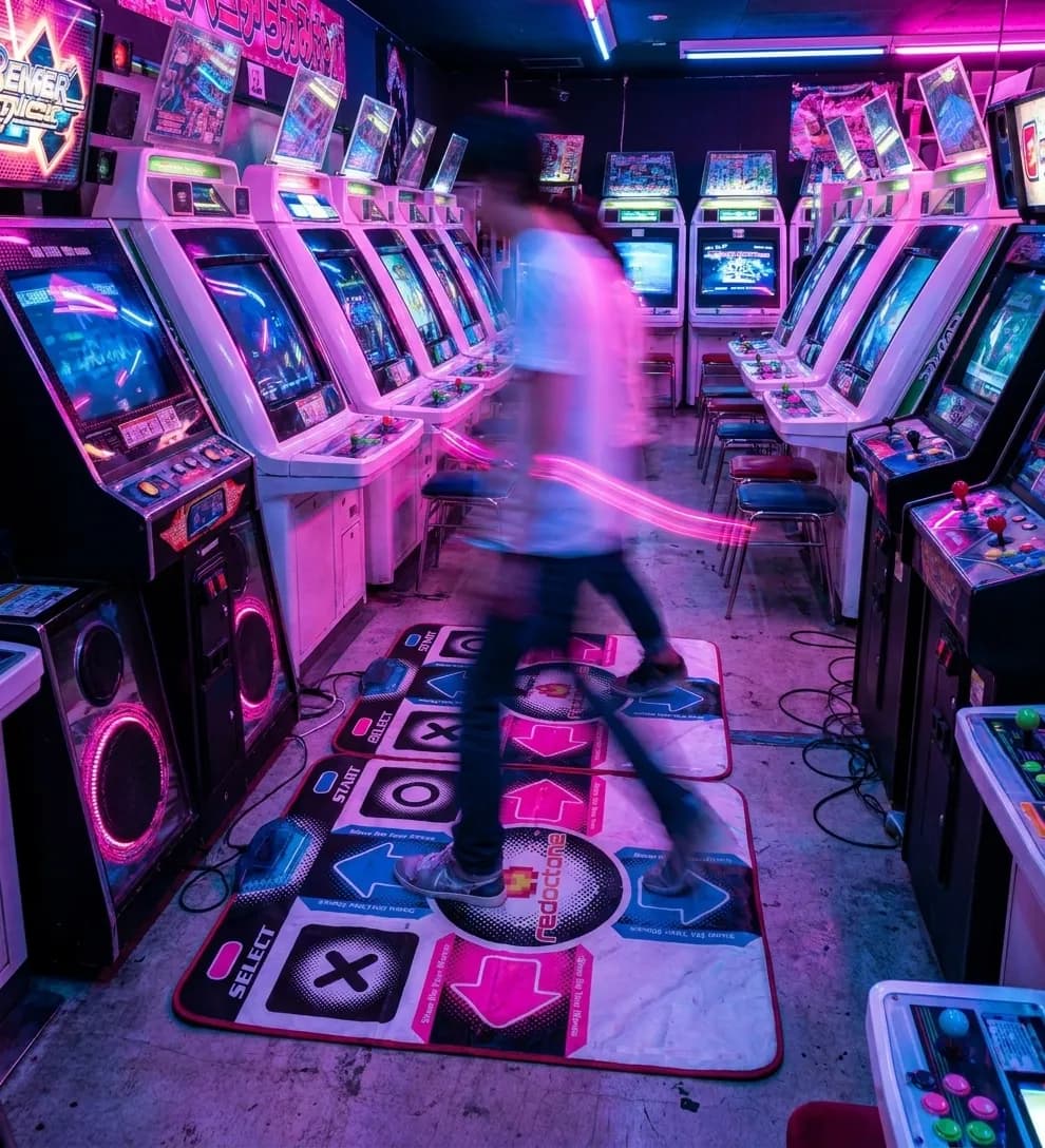 Rows of illuminated arcade machines with colorful screens and neon lighting in an indoor entertainment venue