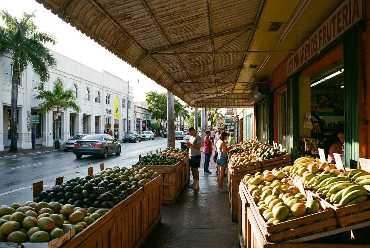 Open-air fruit market stalls with wooden crates of avocados and tropical fruit under metal awning in Little Havana