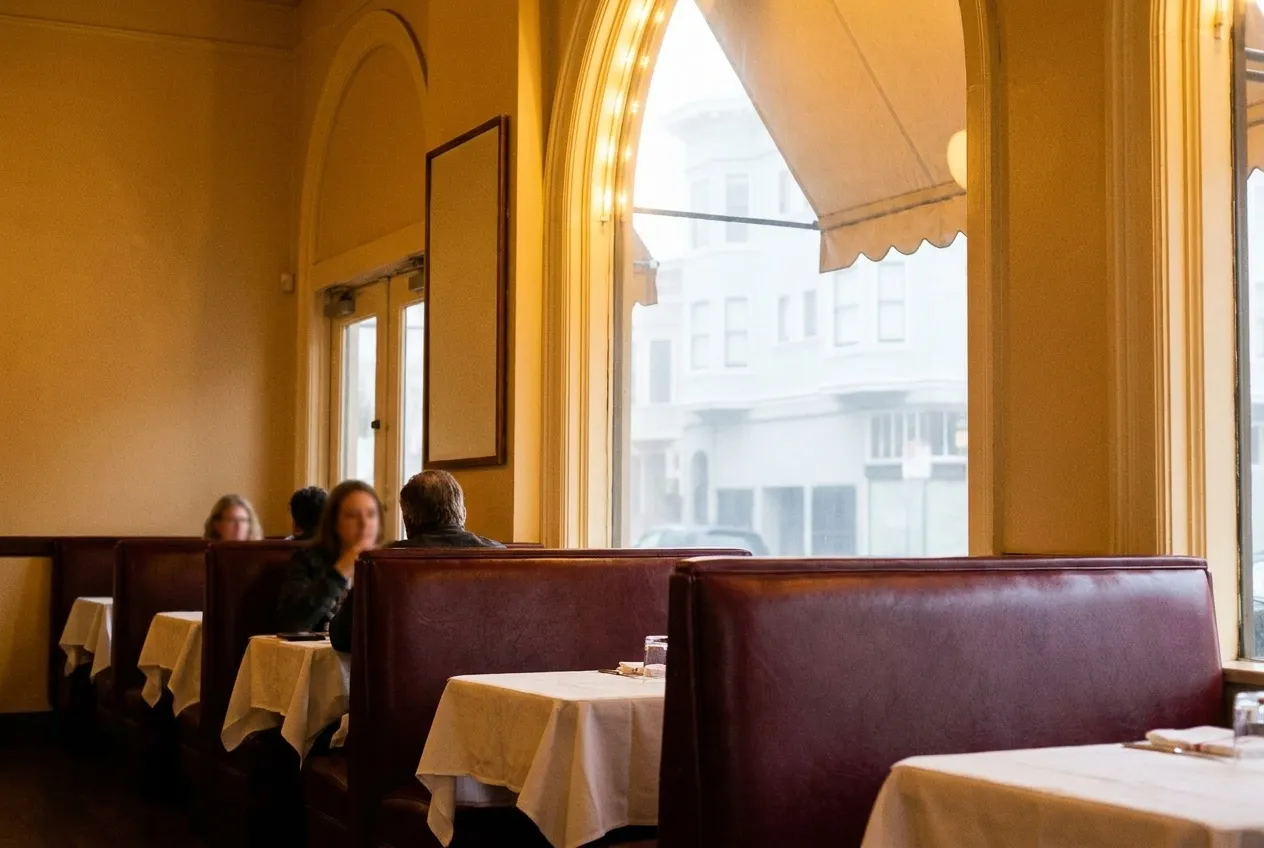 An old-school restaurant interior with maroon leather booths and white tablecloths in San Francisco
