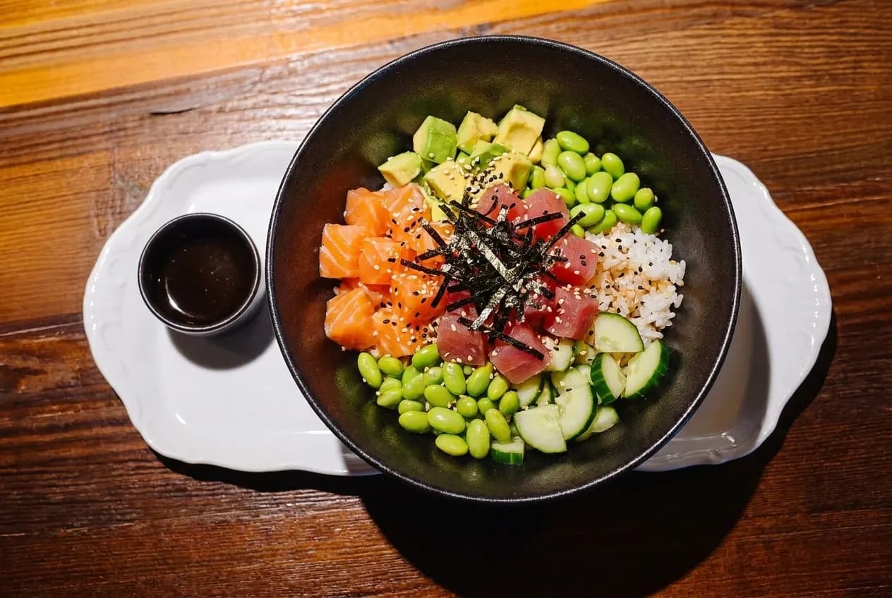 A poke bowl with cubed raw fish, rice, seaweed and avocado photographed from above