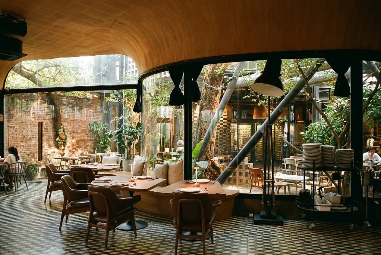 A leafy restaurant courtyard with mismatched chairs and dappled shade in Los Angeles