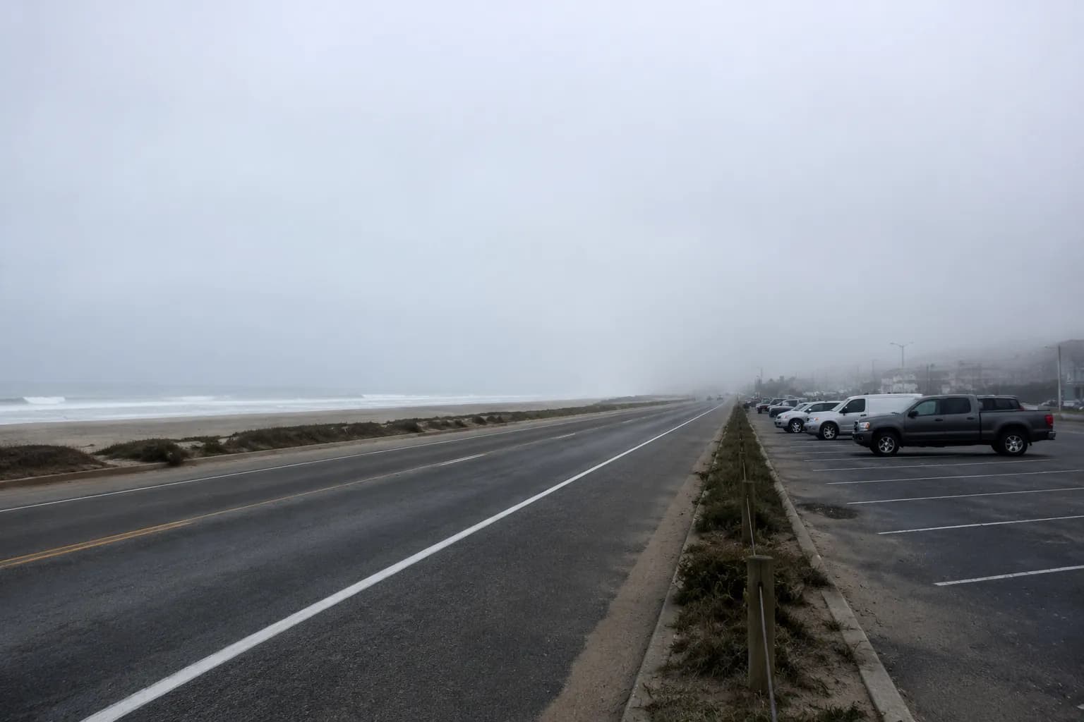 Foggy morning view along the Great Highway at Ocean Beach in San Francisco with ocean and parked cars