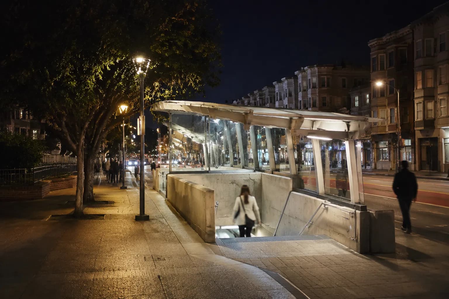 Castro Muni station entrance at night with lit canopy and surrounding buildings in San Francisco