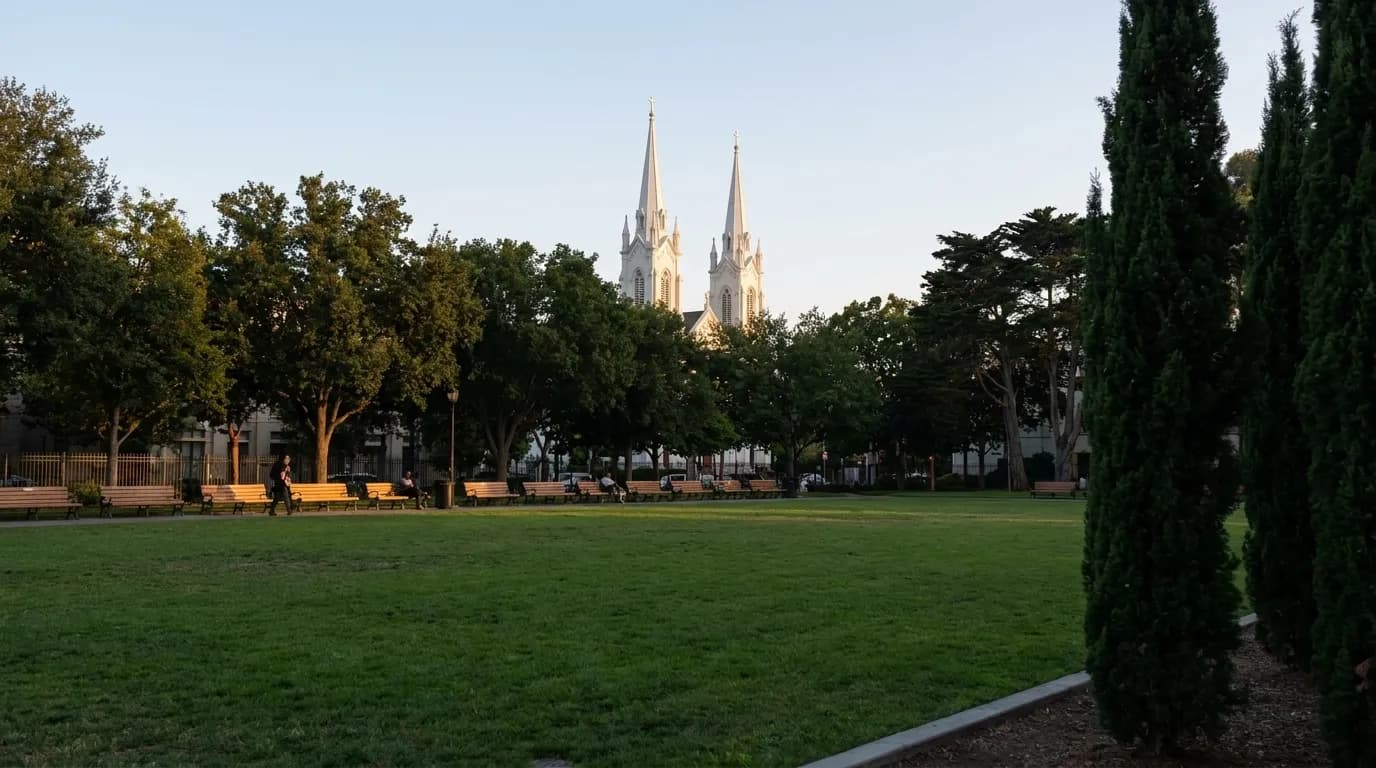 Washington Square Park at dusk with benches under trees and Saints Peter and Paul Church spires in background