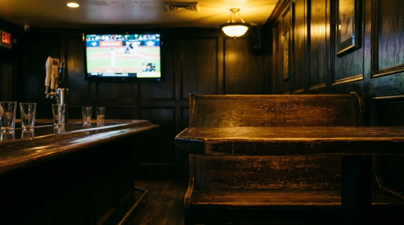 Interior of a San Francisco sports bar with wooden booth and television screen in dim lighting