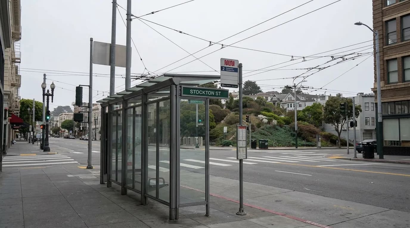 Muni bus stop shelter on Stockton Street with overhead wires and a steep hill in the background