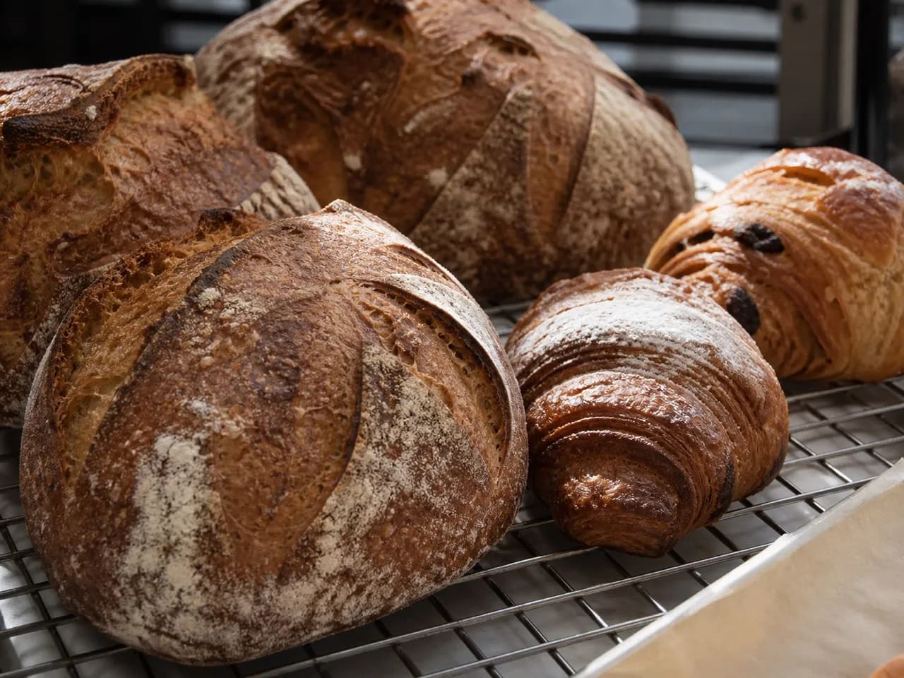 Sourdough loaves and morning pastries on a bakery rack
