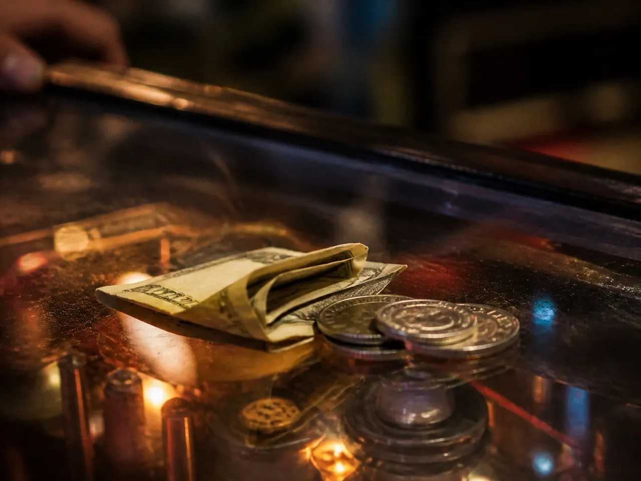 Coins and tokens on the glass of a pinball machine