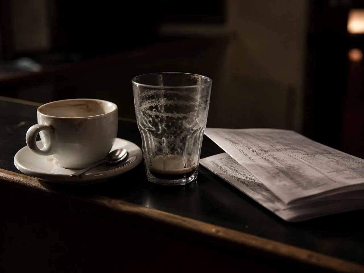 Coffee cup and a half pint on a pub table at dawn