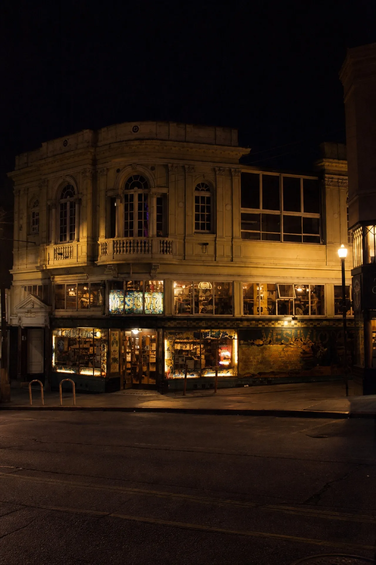 North Beach corner at night with lit ground-floor windows and a dark upper facade