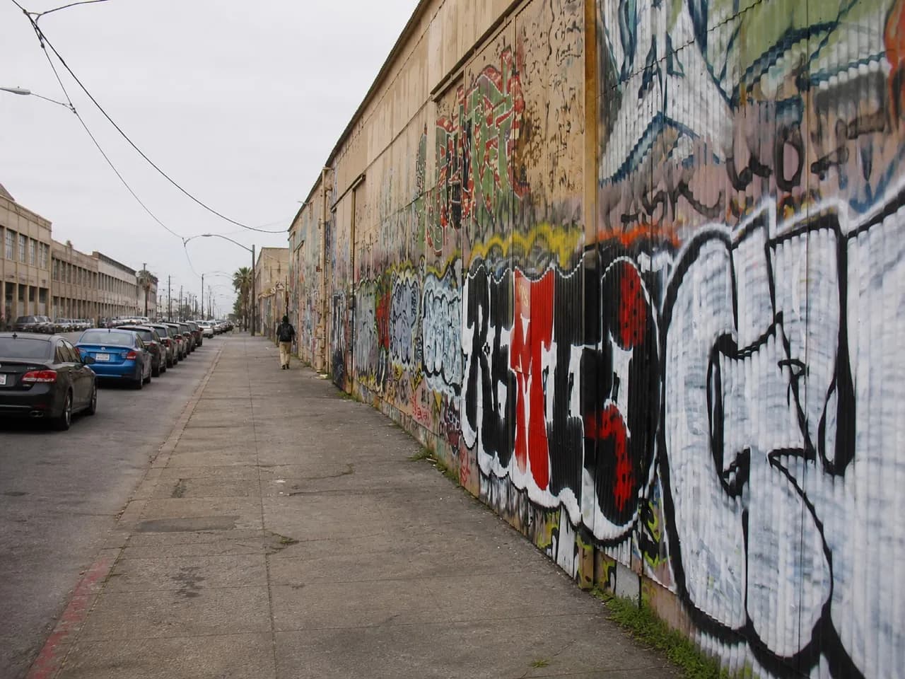 Flat Dogpatch street with warehouse frontages and parked cars