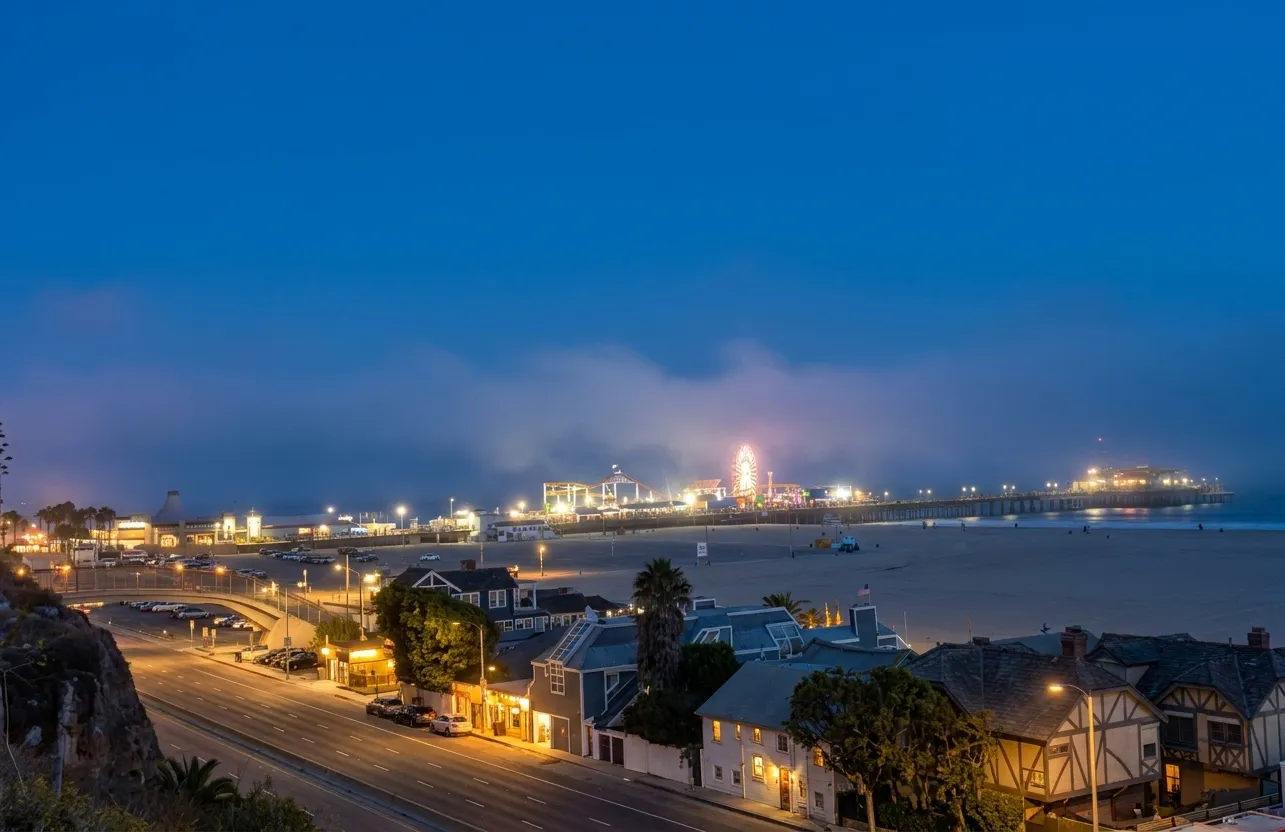 Santa Monica Pier entrance at dusk with iconic arch and Pacific Park lights beginning to glow