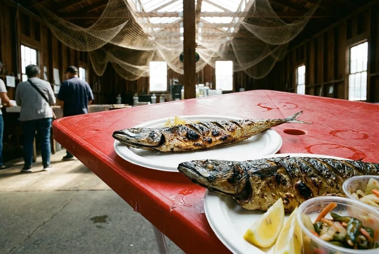 Grilled whole mackerel on paper plate at outdoor market table in Los Angeles