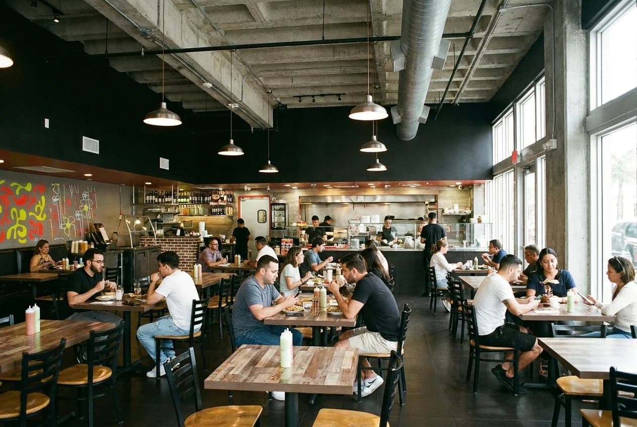 Interior dining room at Manta Wynwood with wooden tables and pendant lighting during lunch service