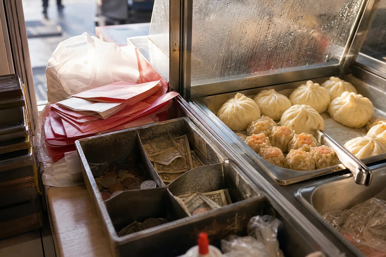 Close-up of a steel steam tray of pork buns and dumplings on a small San Francisco takeout counter