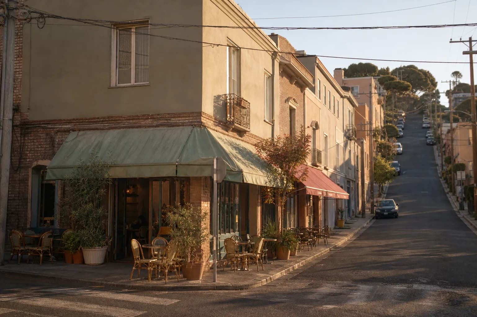 Low-rise San Francisco neighborhood corner with awnings and sidewalk tables in late afternoon sun