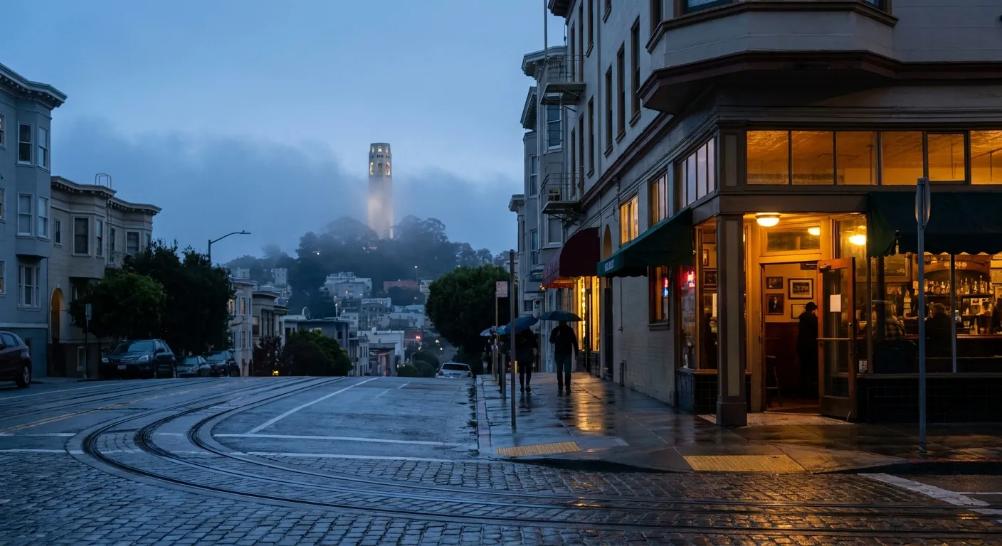 Corner bar exterior glowing at dusk in San Francisco's North Beach with cable car tracks and Coit Tower in the distance