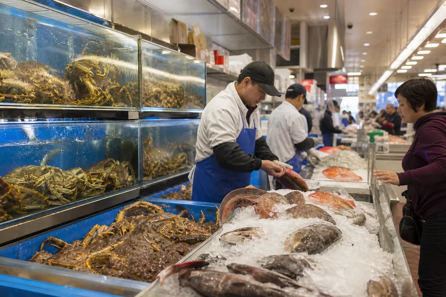 The bustling hot deli and roasted meats counter inside 99 Ranch, featuring hanging roast ducks and crispy pork belly behind glass.