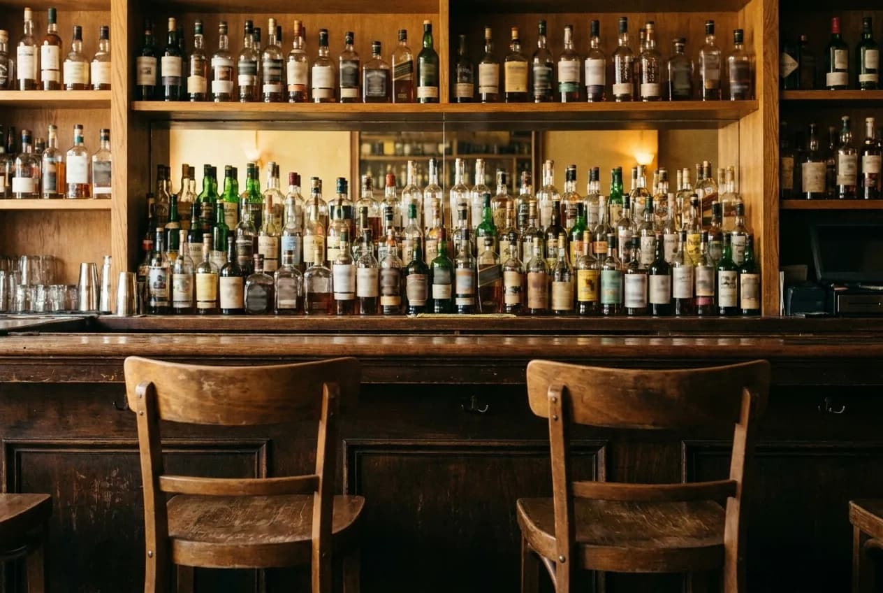 A wall of tequila bottles on shelves behind a small bar