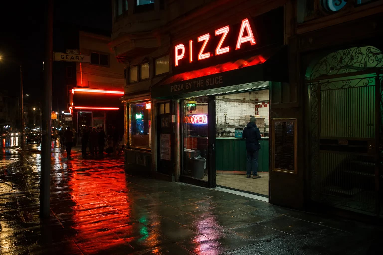 The exterior of a San Francisco pizza shop on Geary Boulevard illuminated at night.