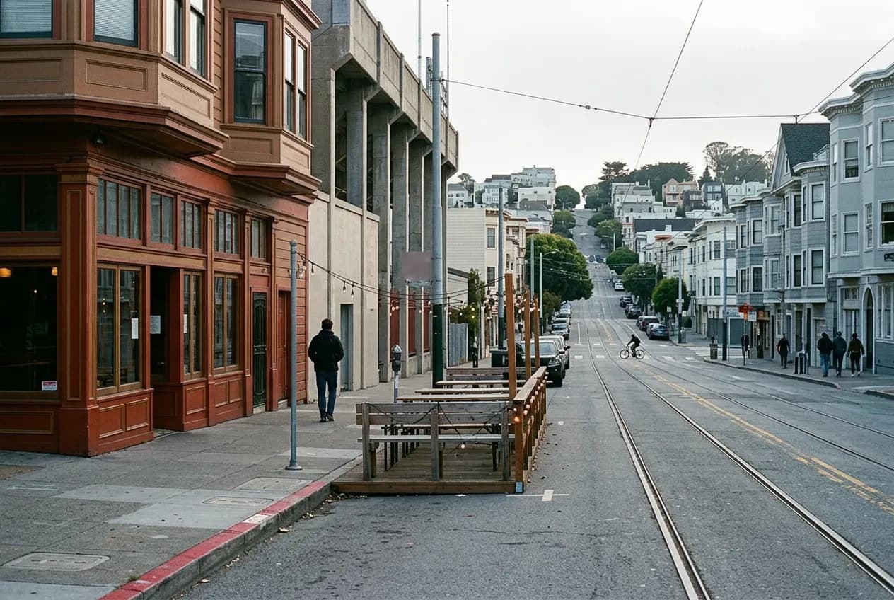 Street-level view of a Cole Valley pub facade on Stanyan Street with outdoor parklet seating across from a stadium wall