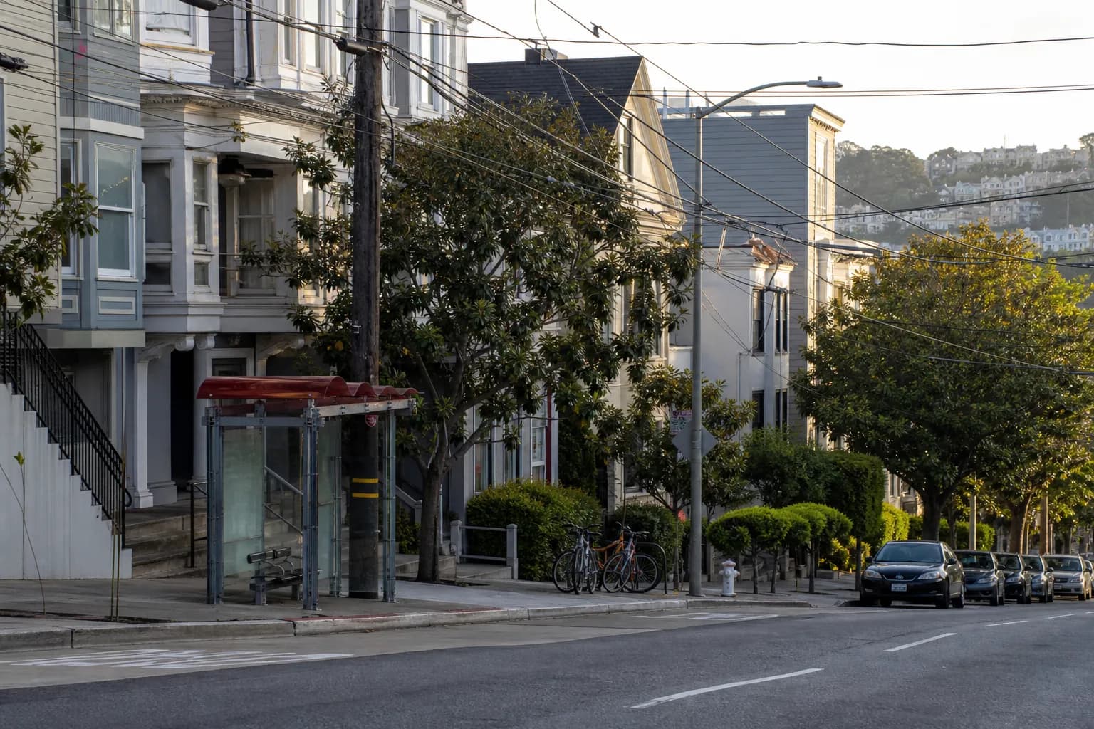 A quiet Noe Valley street with residential buildings and a transit stop near after-school foot traffic