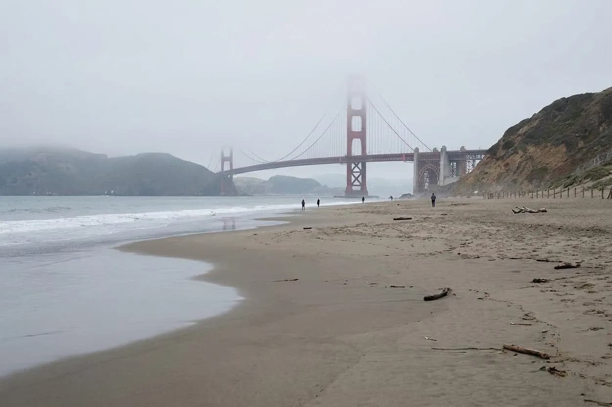 Wide foggy view of Baker Beach with the Golden Gate Bridge in San Francisco