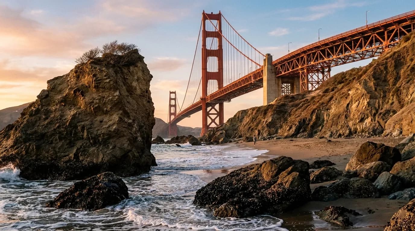 A narrow beach below steep cliffs with the Golden Gate Bridge rising immediately to the north.