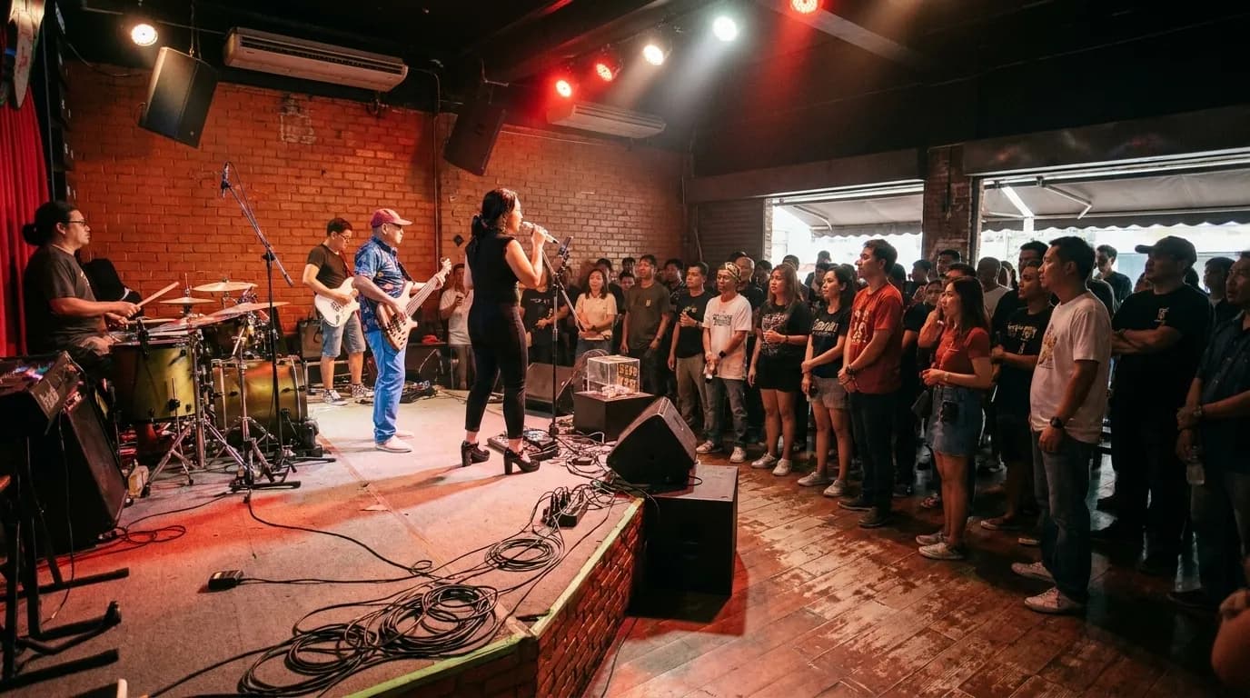 A four-piece band on a low corner stage in a small, dark room with the audience only a few feet from the microphones.