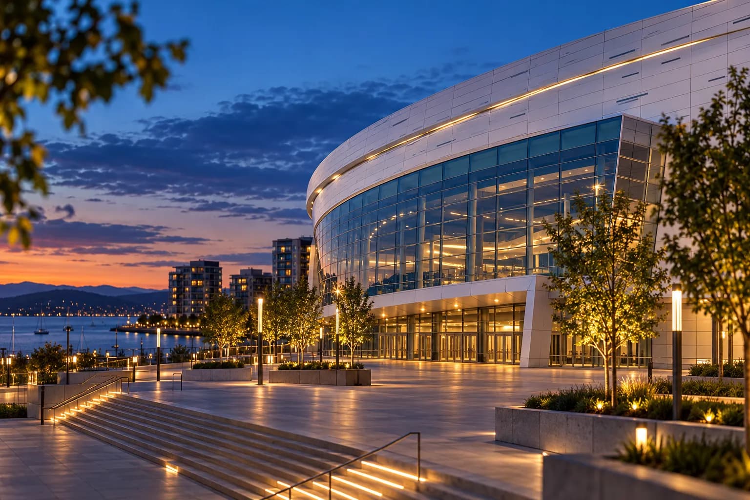 A modern arena with a large public plaza in front at dusk