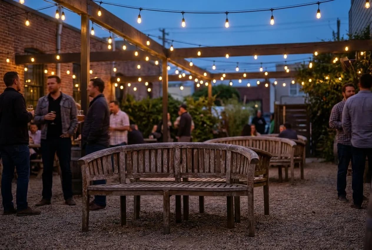 Wooden benches under string lights in an outdoor drinking yard at dusk