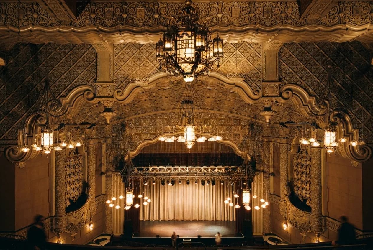 An old music hall interior with a balcony rail and warm hanging lights