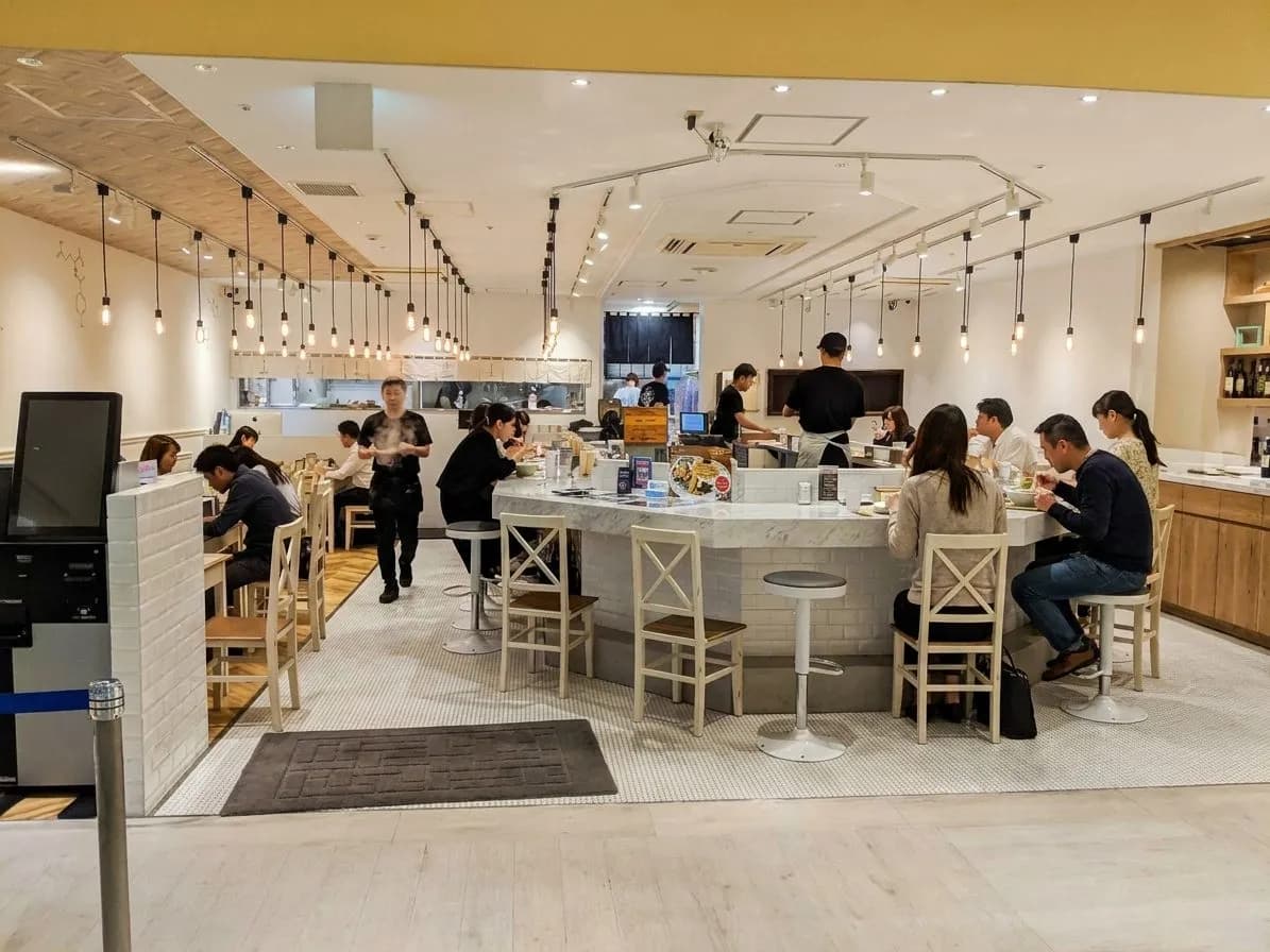 Busy ramen counter with bowls and diners at a Tokyo-born SF shop