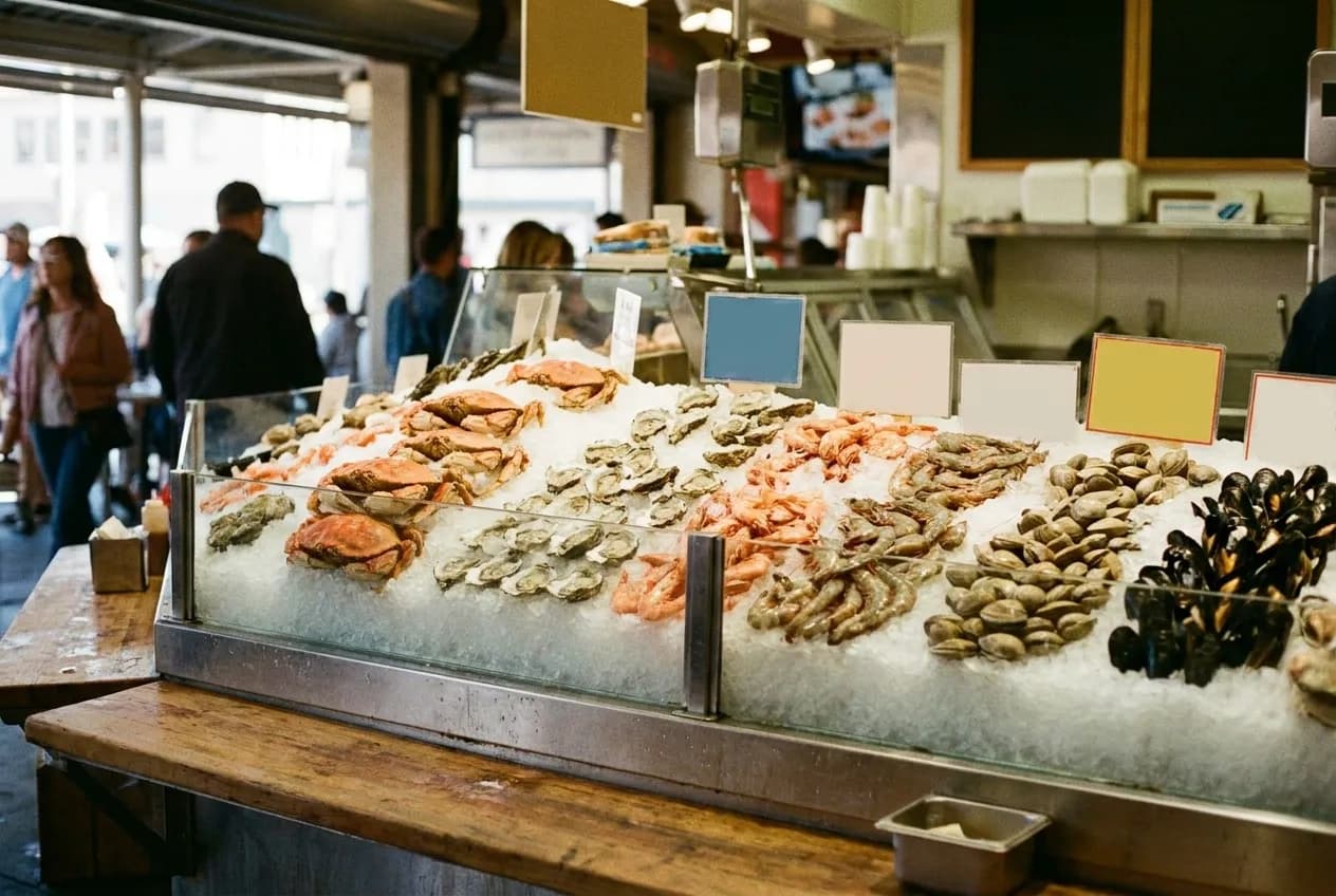 A seafood counter on crushed ice, shellfish laid out in rows behind glass