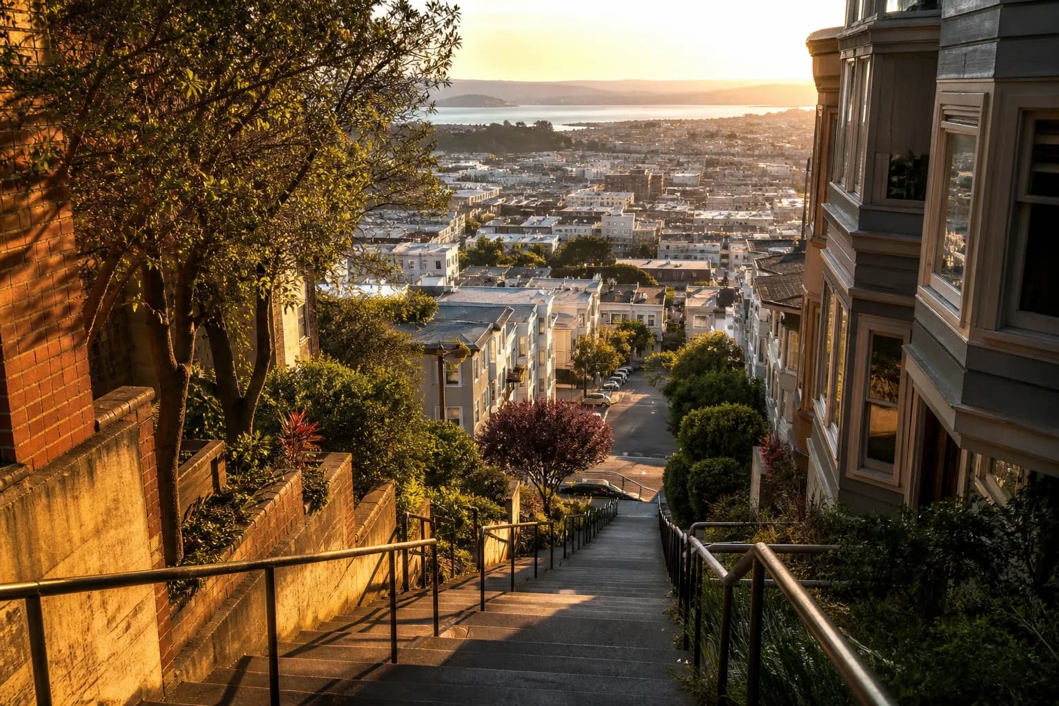 Sunset view down a steep San Francisco stairway toward the Bay and city lights