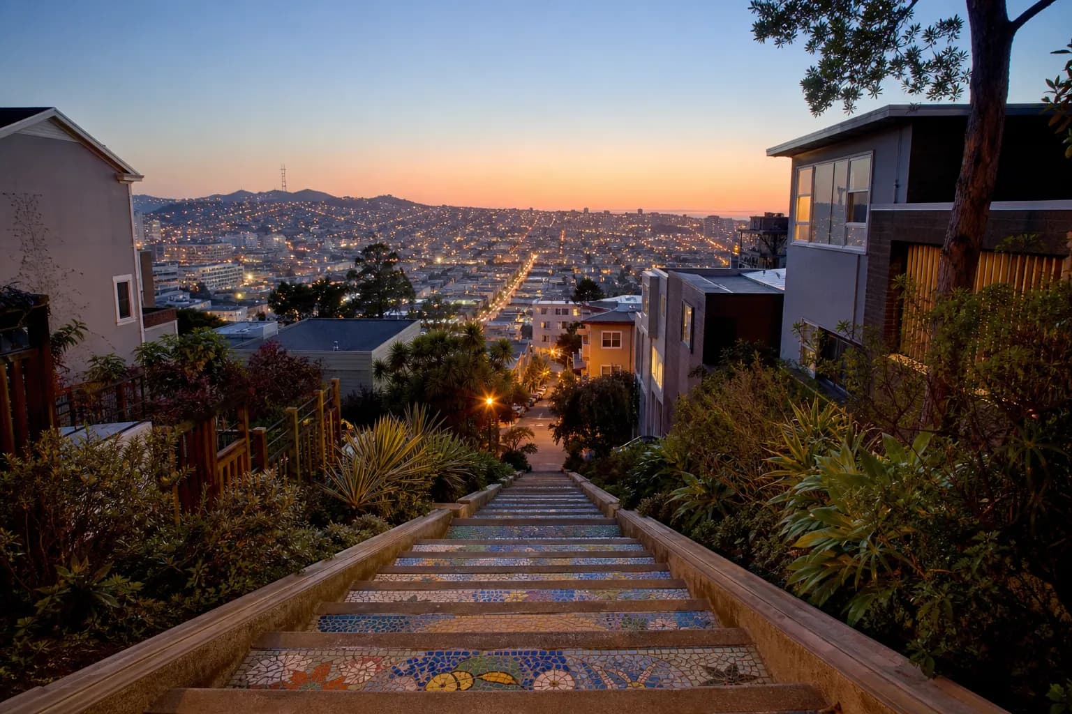 Colorful tiled hillside steps with the city glowing at dusk