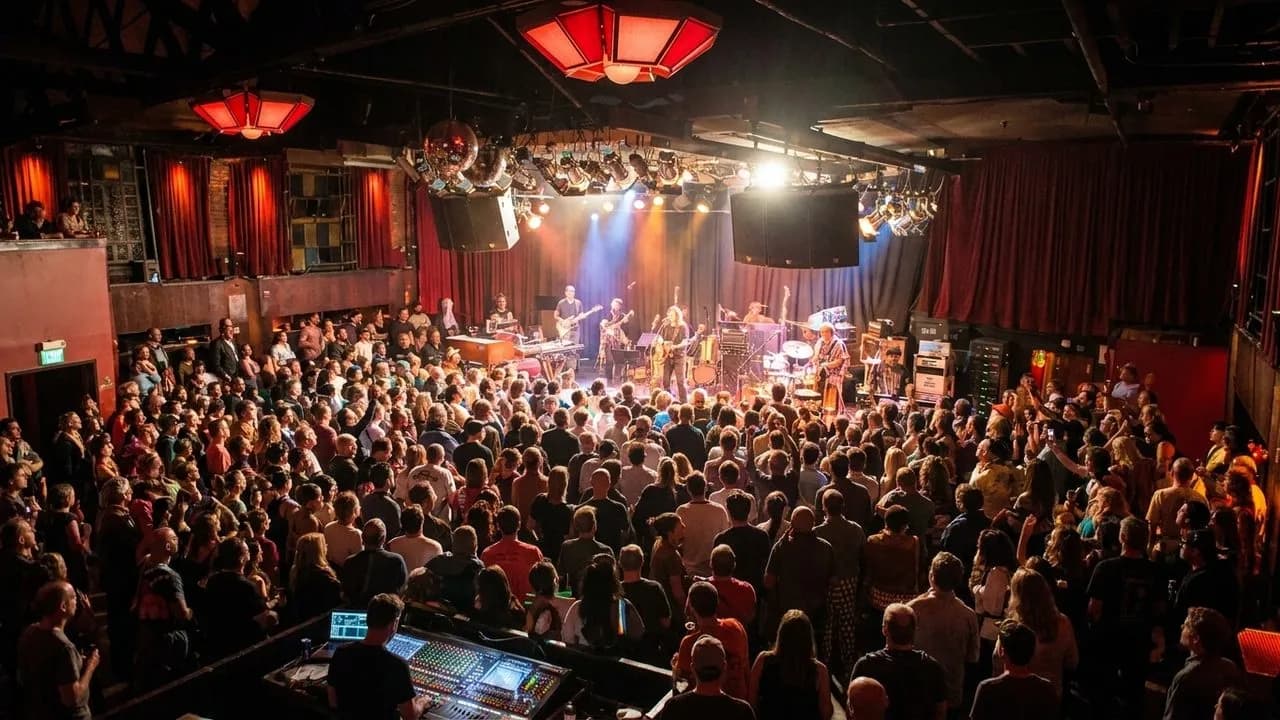 A packed San Francisco concert room with stage lights and attentive crowd
