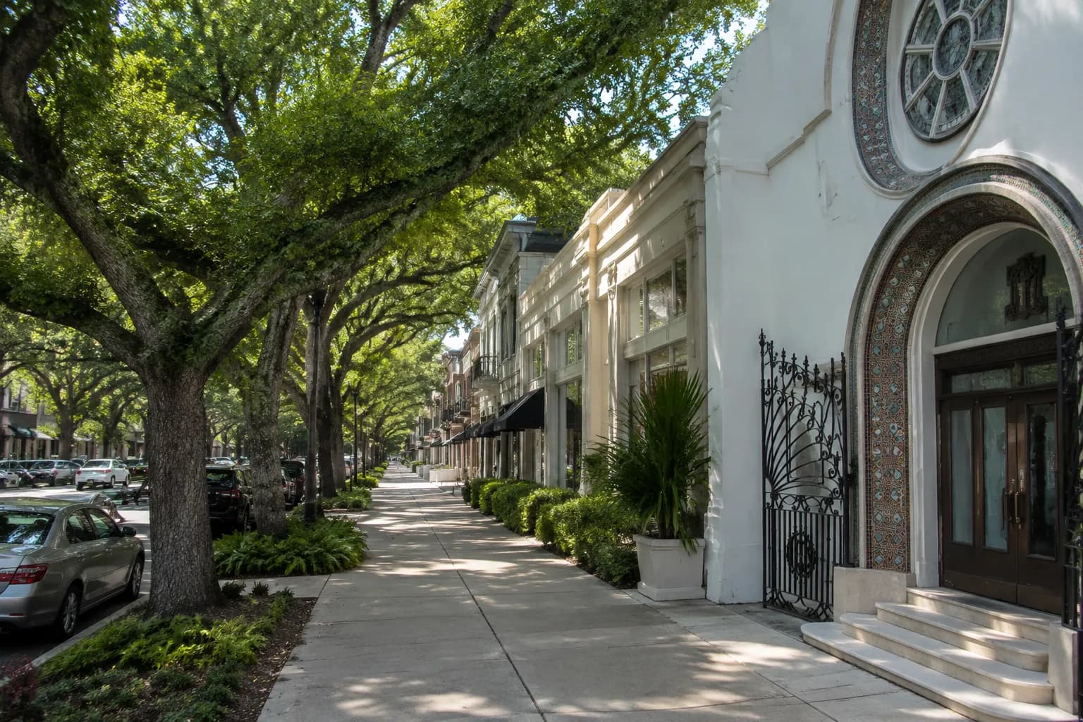 Tree-shaded sidewalk in Coral Gables with retail shops in background