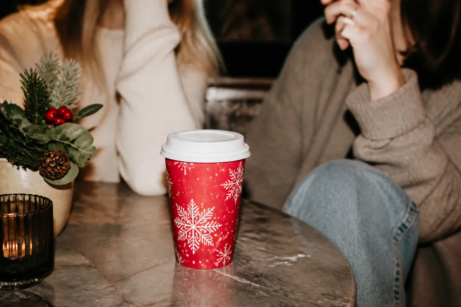 A festive red seasonal coffee cup resting on a table