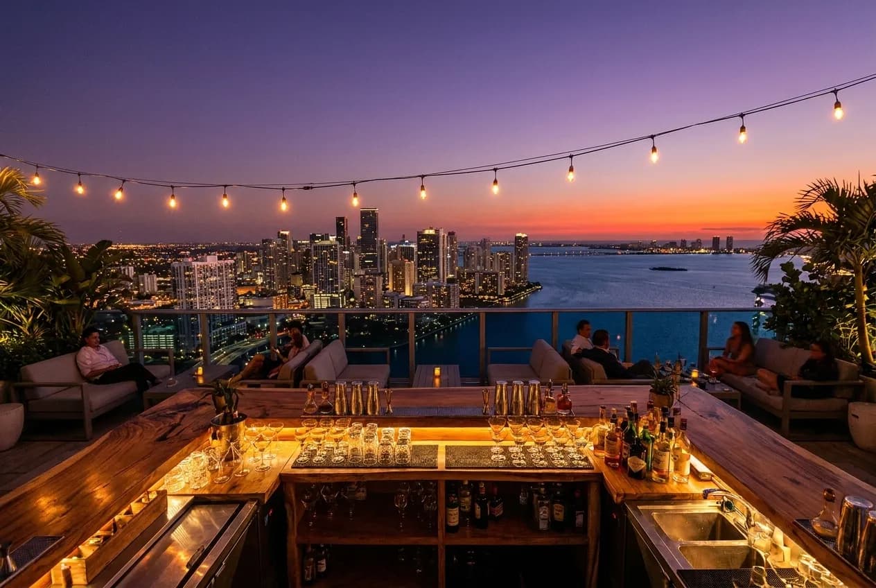 Wide rooftop bar view overlooking Miami skyline and Biscayne Bay at twilight from a high-rise venue