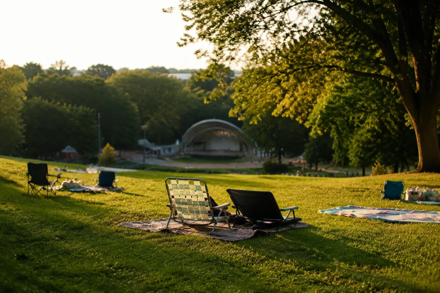 Empty lawn at Prospect Park bandshell in late afternoon, with blankets laid out before an evening concert