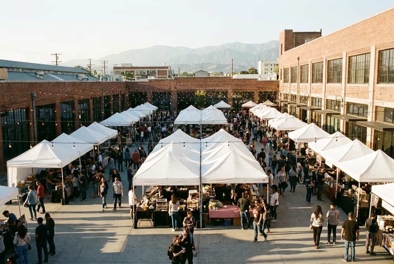 Wide view of Smorgasburg food market with vendor tents and crowds in a Downtown Los Angeles courtyard during late afternoon