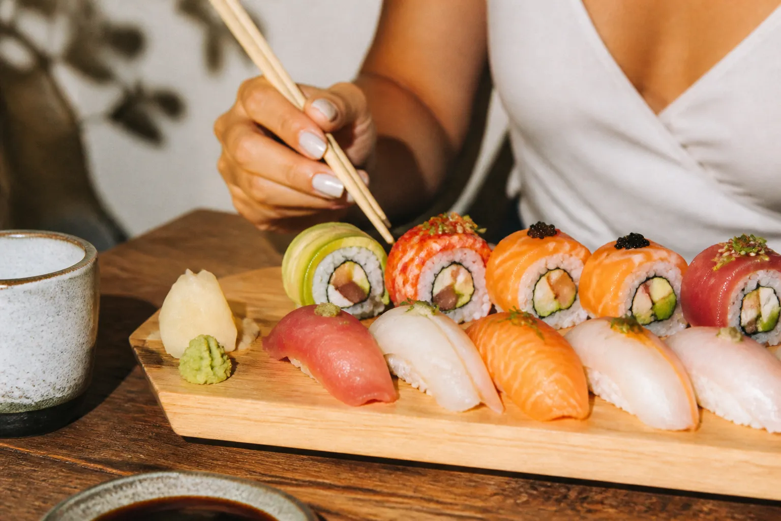 A wooden sushi board with fresh nigiri and colorful rolls under soft natural light
