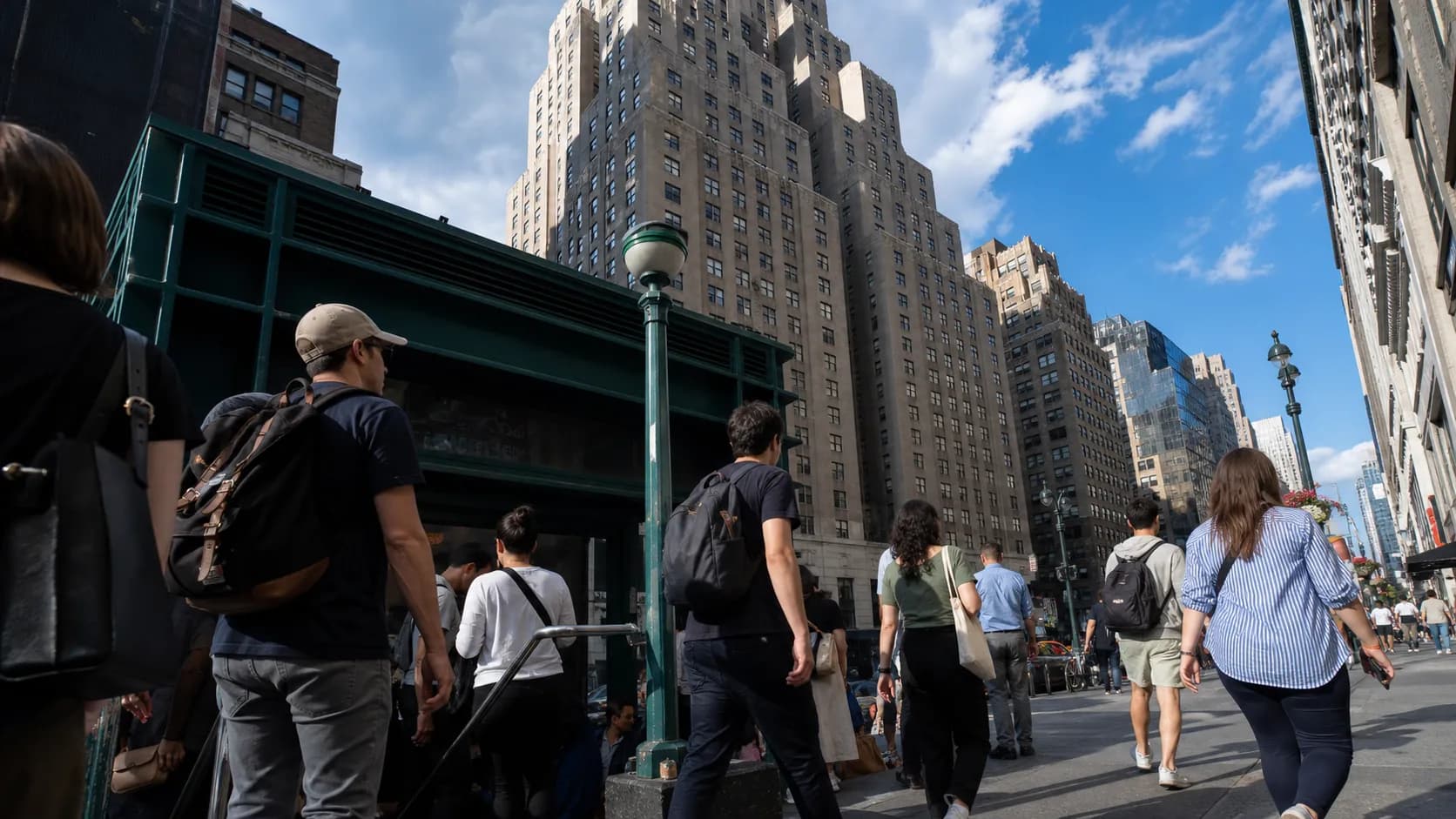 Commuters near a Penn Station subway entrance on a busy Midtown Manhattan sidewalk.