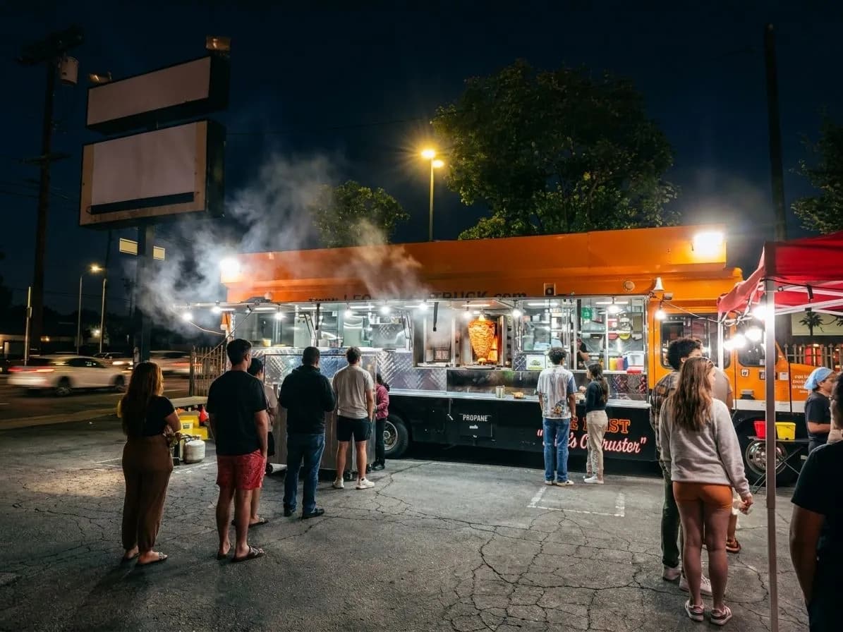 Late-night taco truck scene in Los Angeles with a glowing grill and customers at the curb
