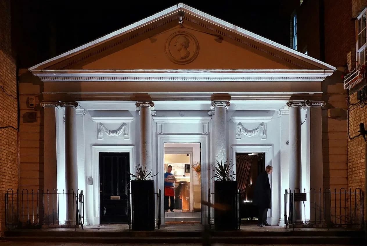 A restaurant facade at night with no signage and a single lit doorway