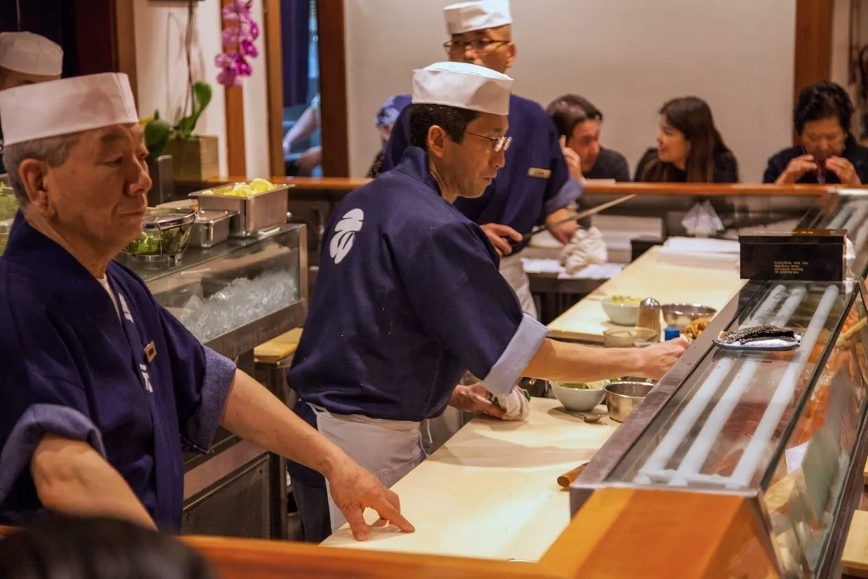 A sushi chef working behind a busy wooden counter in Little Tokyo
