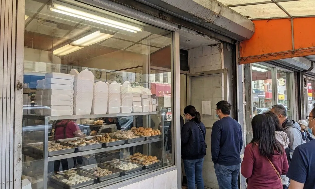 Busy Chinatown dim sum counter with trays of pastries and takeout boxes in San Francisco